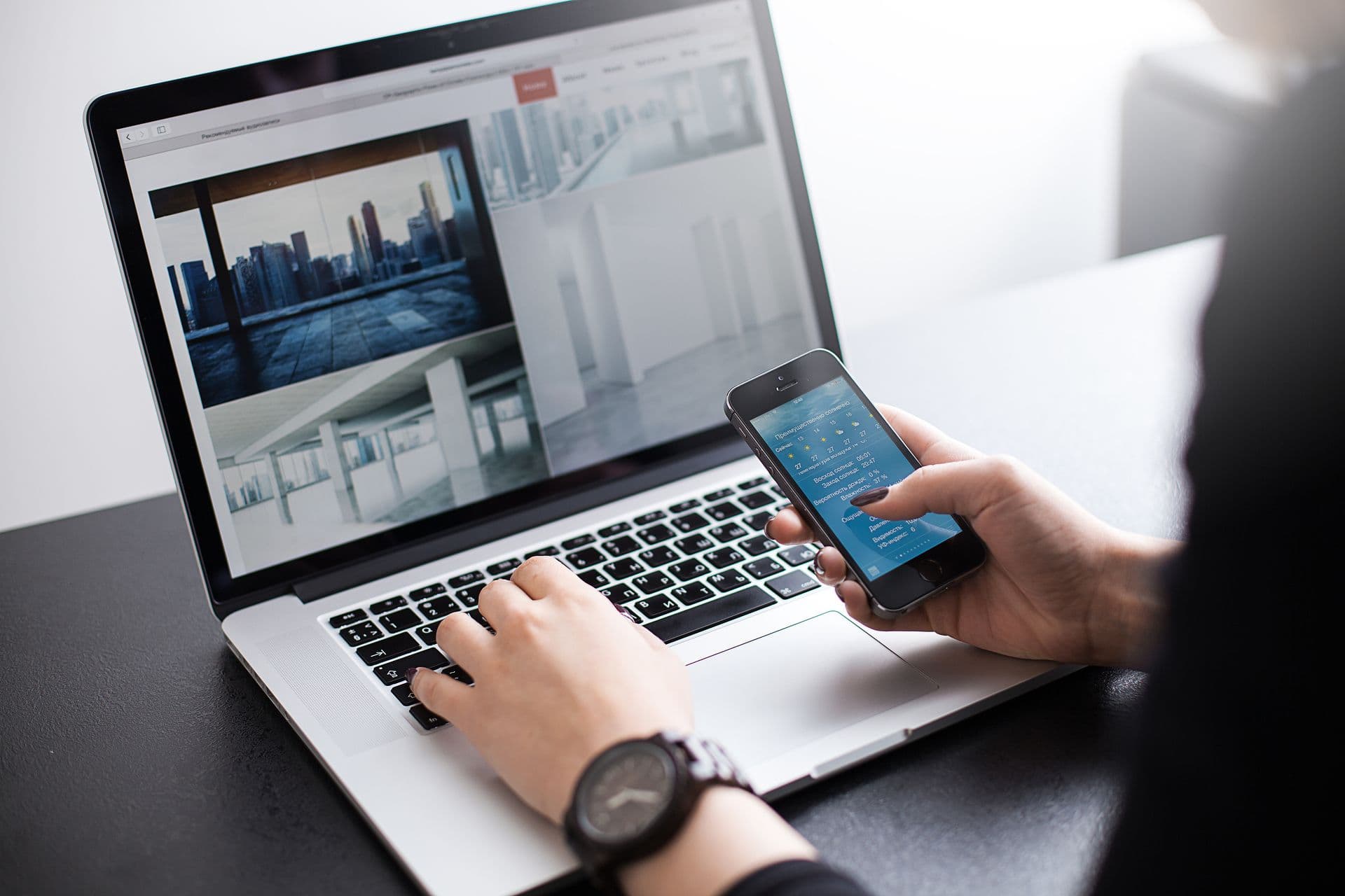 Shot of a young woman working with laptop, woman's hands using notebook computer and smart phone, woman at her workplace using technology, flare cold light